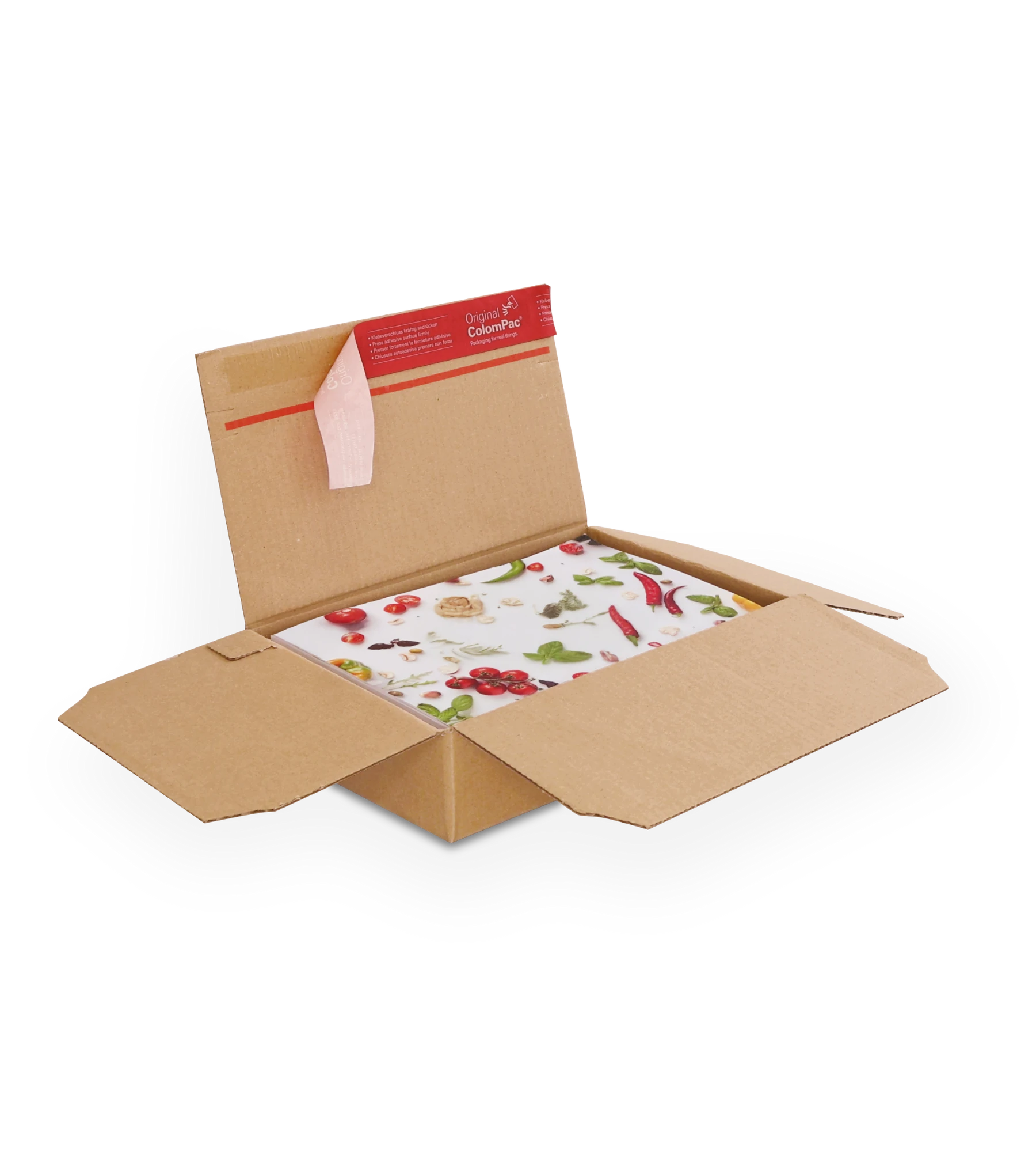 Geöffneter brauner Versandkarton aus Wellpappe mit einem bunten Schneidebrett, das mit Motiven von Gemüse und Kräutern bedruckt ist. Auf der oberen Klappe ein roter ColomPac-Selbstklebeverschluss.