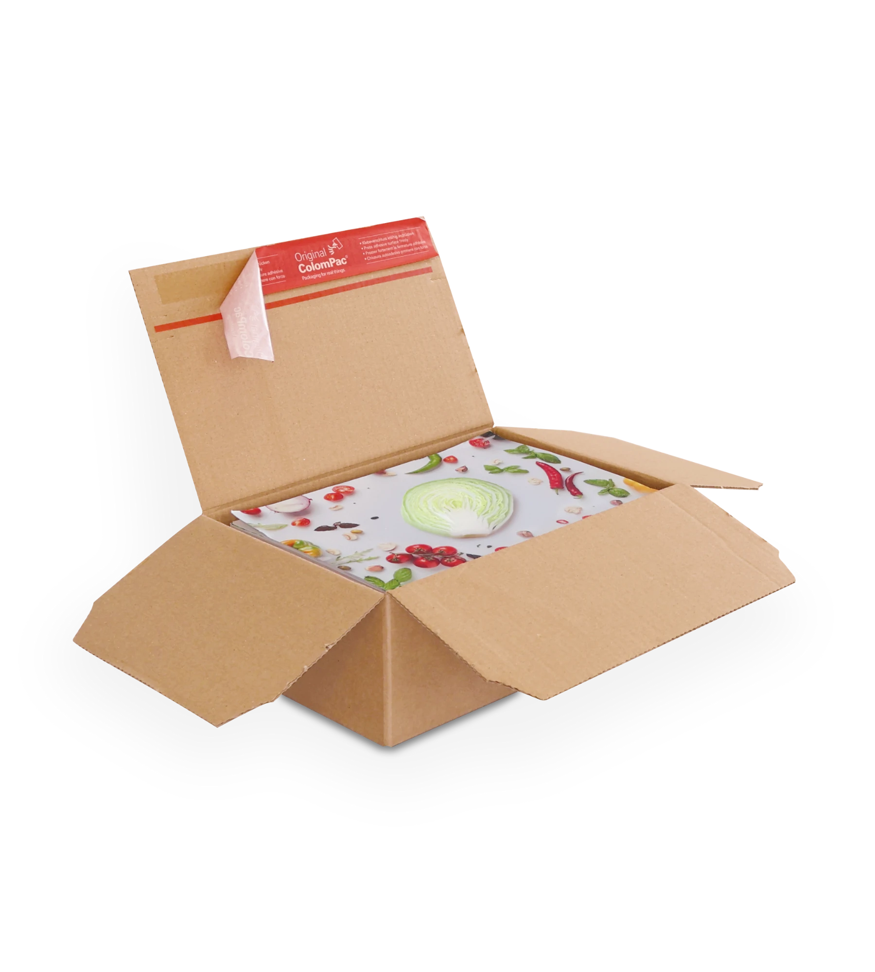 Geöffneter brauner Versandkarton aus Wellpappe mit einem bunt gestalteten Paket, das Gemüse und Obst zeigt – zentral ein Kohlkopf. Auf der oberen Klappe ein roter ColomPac-Selbstklebeverschluss.