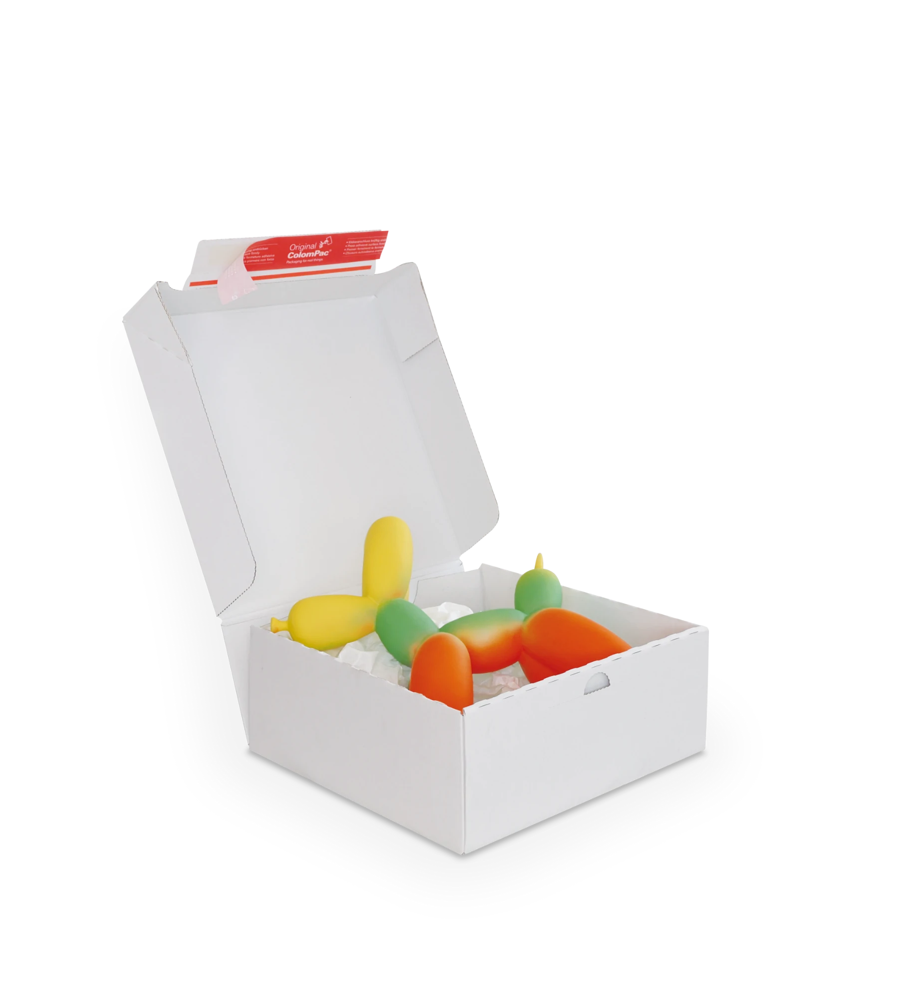 Geöffneter weißer Versandkarton enthält farbige Kerzen in Form von Ballontieren. Die Kerzen sind in Gelb, Grün und Rot gehalten. Auf der Innenseite des Deckels befindet sich ein roter ColomPac-Selbstklebeverschluss.