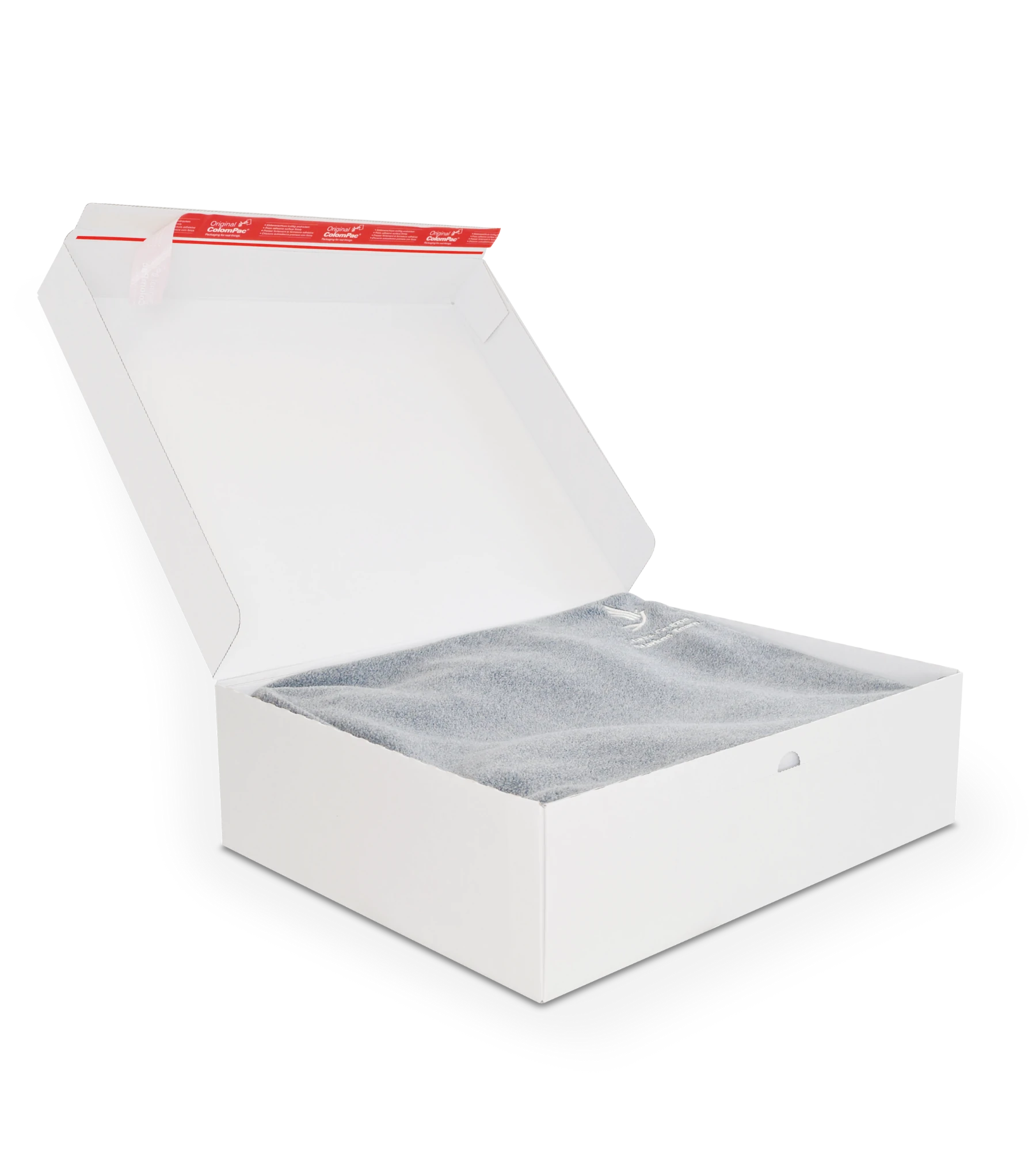 Geöffneter weißer Versandkarton mit roten ColomPac-Selbstklebeverschluss auf der Innenseite des Deckels enthält ein gefaltetes graues Stoffstück, möglicherweise ein Handtuch oder eine Decke.